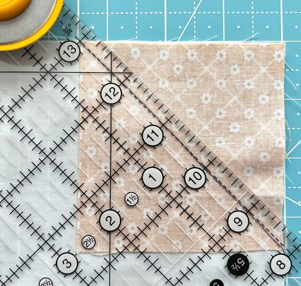 Place a ruler on the stitched line and Trim away the snowball quilt block corners leaving a 1/4